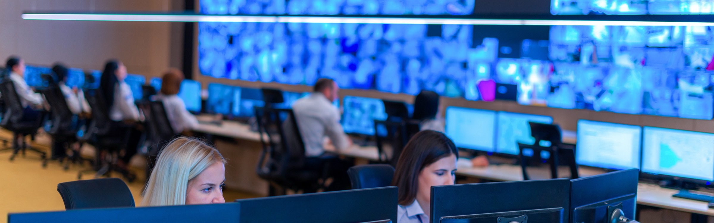 Analysts monitoring a wall of live data and camera feeds in an operations centre.